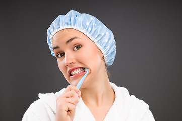 Image showing The morning routine takes forever. a young woman brushing her teeth against a studio background.