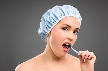 Image showing Brushing your teeth can be so arduous. a young woman brushing her teeth against a studio background.