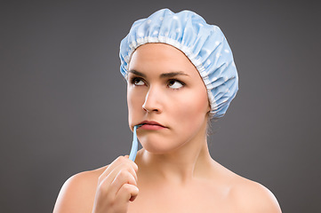 Image showing This is the last thing I wanted to do. a young woman brushing her teeth against a studio background.