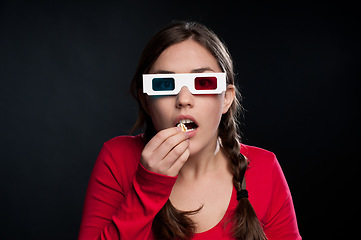 Image showing A gripping thriller. a young woman eating popcorn against a studio background.