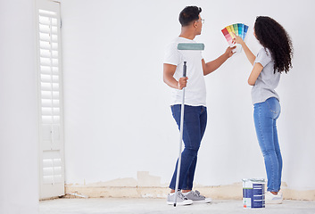 Image showing We need a little color in here. a young couple looking at color swatches while painting a room.