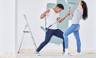 Image showing DIY is always more fun. a young couple dancing while busy painting a room.