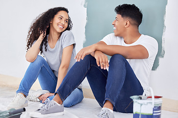 Image showing I cant believe how good we are at this. a young couple painting a wall in a room together.