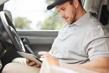 Image showing Whats the address again. a handsome young delivery man using a tablet while sitting in his van.