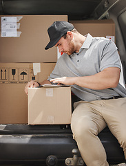 Image showing Marking off deliveries as he goes. a handsome young delivery man using a tablet while sitting in the back of his van.