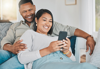 Image showing They even have joint social media accounts. a young couple using a cellphone while relaxing together at home.