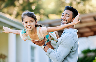 Image showing I can fly if I want. a young father holding up his daughter in the garden outside.