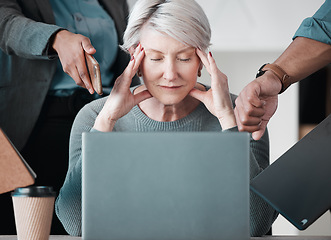 Image showing These interns will be the death of me. a senior businesswoman sitting in the office and feeling stressed while her colleagues put pressure on her.