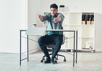 Image showing Get out of my face. Full length shot of a handsome young businessman sitting alone in the office and throwing his laptop in anger.