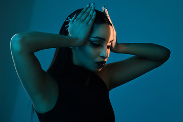 Image showing Style dilemma. Conceptual shot of a stylish young woman posing in studio against a blue background.