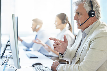 Image showing We provide solutions as fast as we answer your call. a mature man wearing a headset while working in a call center.