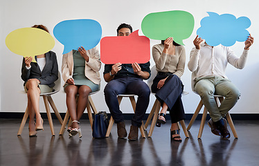 Image showing Everyone has a right to their own opinion. a group of young businesspeople holding speech bubbles while waiting in line.