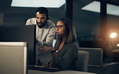 Image showing Lets troubleshoot some more. two call centre agents working together in an office at night.