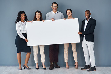 Image showing Why not advertise your business on this platform. Portrait of a group of businesspeople holding a black poster while standing against a grey background.