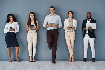 Image showing Striking new connections while waiting. Portrait of a group of businesspeople using digital devices while standing in line against a grey background.