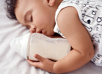 Image showing Snack time turned into nap time. an adorable baby boy sleeping with his bottle of milk on the bed at home.
