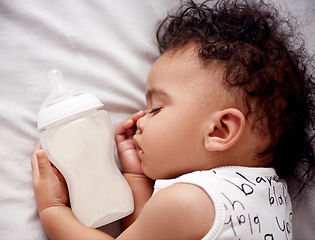 Image showing My precious. an adorable baby boy sleeping with his bottle of milk on the bed at home.