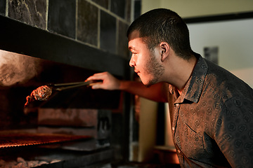 Image showing The man in charge of the barbecue. a young man grilling meat while having a barbecue.