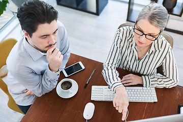 Image showing Putting their heads together to make the right choices. High angle shot of two businesspeople working together on a computer in an office.