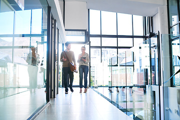 Image showing Striving towards success together. two businesspeople using a digital tablet together while walking in an office.