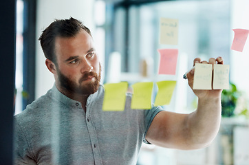 Image showing I hope this concept works out well. a young businessman brainstorming with notes on a glass wall in an office.