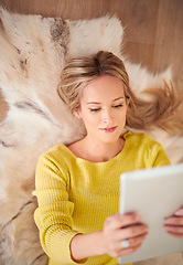 Image showing She looks good fom every angle. A young woman lying on the ground holding a digtal tablet.