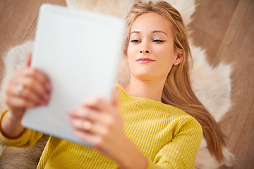 Image showing Her E-book was getting intense. A young woman lying on the floor reading a book on her digital tablet.