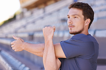 Image showing Take the care to prepare. a handsome young man stretching at an athletics arena.