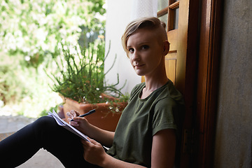 Image showing Shes getting her ideas down. Portrait of an attractive young woman sitting outside on the porch writing in a notepad.