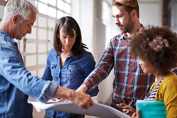 Image showing Coming up with great strategies. A group of colleagues standing in a buliding assessing a blueprint.