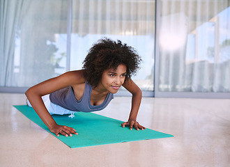 Image showing Getting stronger with each rep. an attractive young woman doing push-ups on an exercise mat.