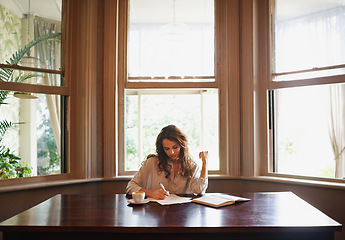 Image showing Shes always writing. an attractive young woman writing in a relaxed environment at home.