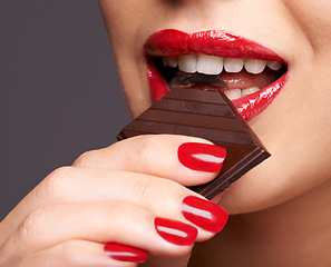 Image showing Every woman needs a guilt-free chocolate day. Closeup portrait of a cute young female biting on a chocolate bar.