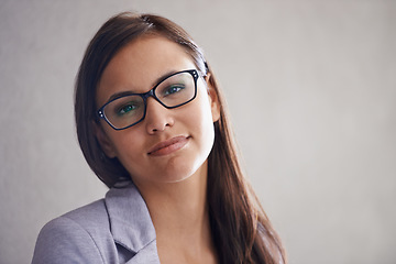 Image showing Happy with her career choices. Portrait of a successful young businesswoman standing against a gray wall.