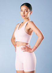 Image showing Mixed race fitness woman standing with her hands on her hips in studio against a blue background. Beautiful young hispanic female athlete exercising or working out. Dedicated to health and fitness