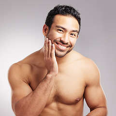 Image showing Handsome young mixed race man touching his face and posing shirtless isolated in studio against a grey background. Hispanic well groomed male looking confident and happy with his daily skincare regim