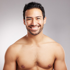 Image showing Handsome young mixed race man shirtless in studio isolated against a grey background. Hispanic well groomed male looking confident and happy with his daily skincare regime. Firm and healthy skin