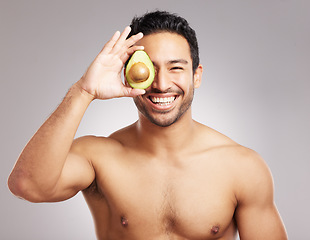 Image showing Handsome young mixed race man posing with an avocado isolated in studio against a grey background. His skincare regime keeps him fresh. For firm skin, eat healthy. Packed with vitamins and nutrients