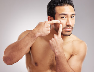 Image showing Handsome young mixed race man posing shirtless in studio isolated against a grey background. Hispanic male popping pimples or zits on his face. No outbreaks in the plans for his skincare regime