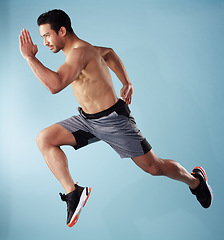 Image showing Fullbody young hispanic man running in studio isolated against a blue background. Mixed race shirtless male athlete running or sprinting to win a race. Endurance training to increase his cardio