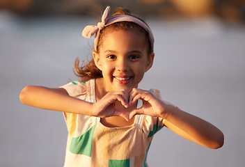 Image showing Shell make you believe in magic again. an adorable little girrl showing a heart shale with her fingers at the beach.