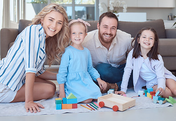 Image showing Happy caucasian family smiling while playing and sitting on the floor together in the lounge at home. Two loving parents spending time with their daughters. Sisters playing with toys together