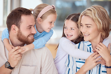 Image showing Happy caucasian family of four being affectionate and positive while embracing their cute little girls on a sofa at home. Young couple enjoying the day with their daughters and having fun together