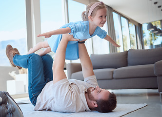 Image showing Happy little girl playing with her father in the lounge. Caucasian father lifting his daughter in the air, lying on the floor at home. Smiling parent having fun with his young daughter