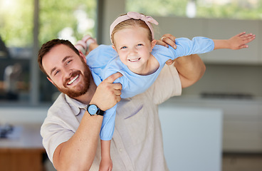 Image showing Adorable little girl pretending to fly while being lifted by dad. Father playing with his adorable daughter at home