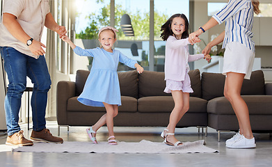 Image showing Excited happy kids having fun with energetic young parents at home. Sisters dancing together with mom and dad. Family having fun dancing to music