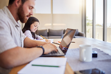 Image showing Father working from home on his laptop. Freelancer dad using laptop while child does schoolwork. Parent working remotely and looking after child