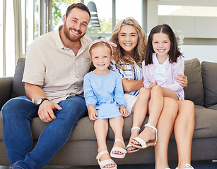 Image showing Portrait of smiling caucasian family relaxing together on a sofa at home. Carefree little girls spending time with loving parents. Happy kids bonding with mom and dad