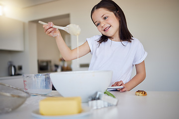 Image showing Happy little girl baking at home. Smart girl mixing ingredients to to bake cake and checking consistency