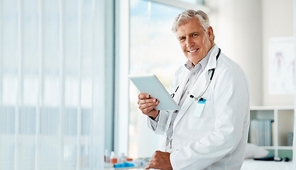 Image showing Happy mature male doctor holding a digital tablet. Smiling senior practitioner using digital tablet to check medical records or results in a hospital